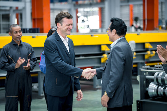 Business partnership and industrial collaboration. Two business professionals discussing inside a modern factory during a site visit. manufacturing, teamwork, industry, meeting, factory