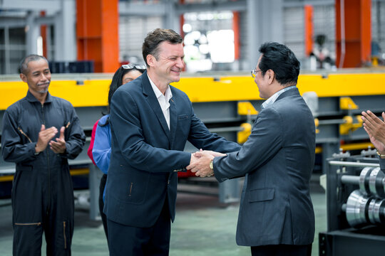 Business partnership and industrial collaboration. Two business professionals discussing inside a modern factory during a site visit. manufacturing, teamwork, industry, meeting, factory