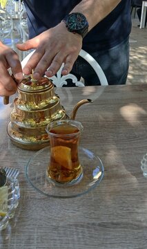 Ein Mann gie&szlig;t Tee aus einer traditionellen Metallkanne in einem Caf&eacute; in Naftalan, Aserbaidschan, ein.