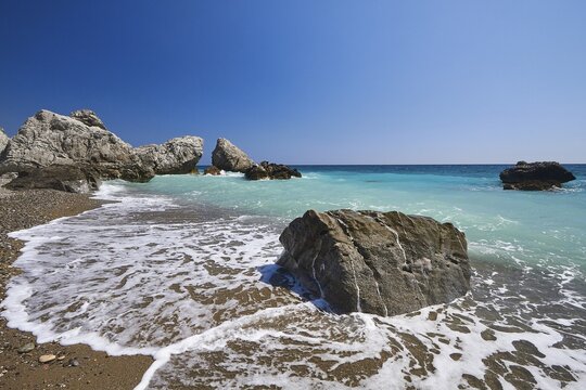 Beach, south coast, green sea, surf, blue cloudless sky, rocks in the sea, near Mirtos, Lassithi province, Crete, Greece