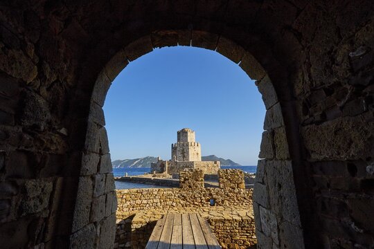 View through an arched entrance to a castle by the sea, octagonal medieval tower. Islet of Bourtzi, sea fortress of Methoni, Peloponnese, Greece
