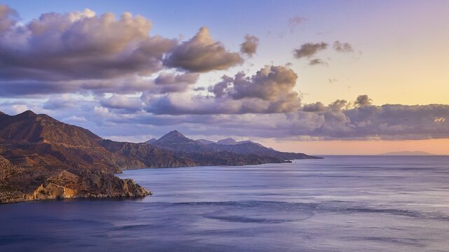 View of the sea and mountains at sunrise, surrounded by pastel-coloured clouds, morning light, sunrise, coastal road, east coast, Karpathos, Dodecanese, Greek Islands, Greece