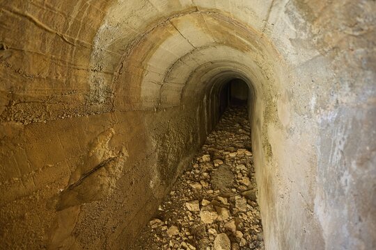 Long and narrow tunnel with stone walls and sparse light, Lost Place, Air Defence Position, Aerophone, Parabolic Acoustic Mirror, Patella Mountain, WW2, west of Lakki, Leros, Dodecanese, Greek Islands, Greece