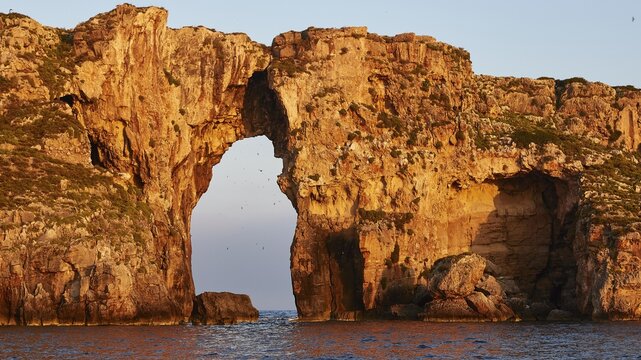 Impressive rock formation with an arch in the sea at sunrise, morning light, Tsichli Babas islet, Navarino Bay, Pylos, Peloponnese, Greece