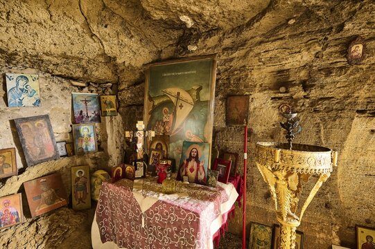 Interior view of a rock cave with an altar decorated with numerous religious pictures and icons, as well as a golden baptismal font, rock church of Agios Nikolaos, Oasis Beach, Kallithea, Rhodes, Dodecanese, Greek Islands, Greece