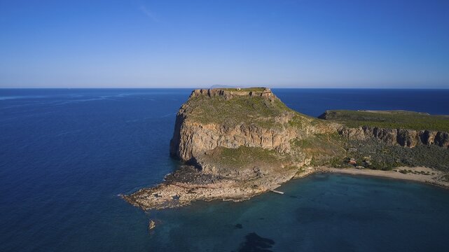Drone shot, Rocky cliff coast with neighbouring beach and clear blue sky over the wide ocean, Venetian sea fortress, Gramvoussa, Gramvoussa peninsula, Pirate bay, Balos, Lagoon, Northwest Crete, Crete, Greek Islands, Greece
