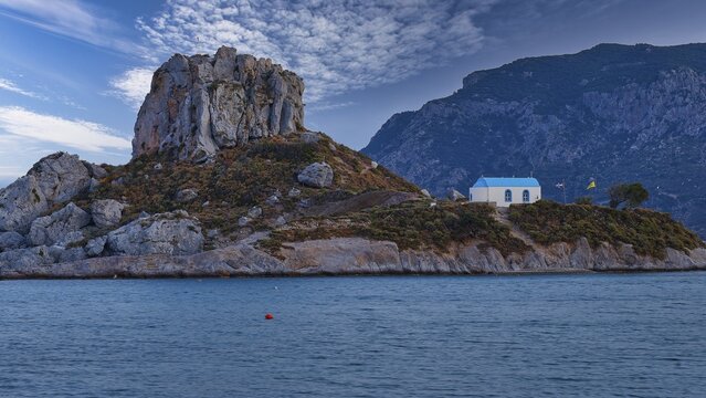 A rocky hill with a blue house by the sea under a cloudy sky, Agios Stefanos Beach, Agios Stefanos Basilica, Basilica, Kastri Island, Kos, Dodecanese, Greek Islands, Greece