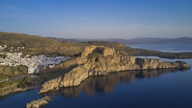 Drone shot, first morning light, Lindos, Acropolis of Lindos, panoramic view of a fortress on cliffs above the sea at dusk next to a village, Archaeological Site, Lindos, Rhodes, Dodecanese, Greek Islands, Greece