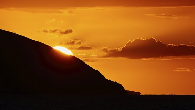 Soft orange light of the sun behind a mountain, cloud formations in the sky, sunset, Kassos, Karpathos, offshore islands, Dodecanese, Greek Islands, Greece
