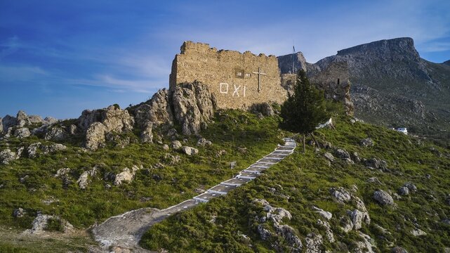 Drone shot, stone ruin on hill with paved path in mountainous landscape under blue sky, Archangelos, castle, place, castle of Archangelos, Rhodes, Dodecanese, Greek Islands, Greece