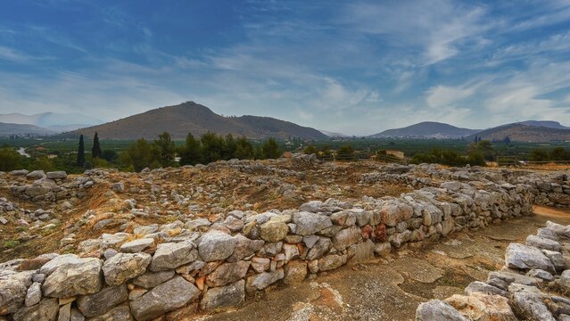Sky replaced, wide landscape view with ruins and mountains in the background under blue sky, Tiryns, ancient city in Argolis, Mycenaean, Peloponnese, Greece