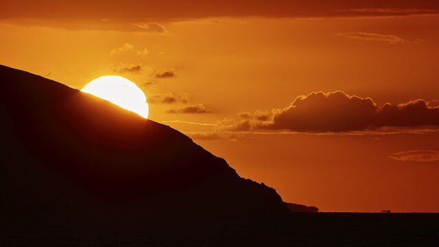 Sun setting behind a mountain, clear silhouette in front of an intense orange sky, sunset, Kassos, Karpathos, offshore islands, Dodecanese, Greek Islands, Greece