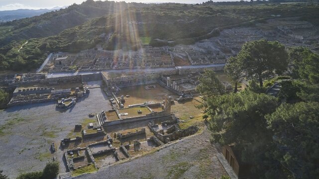 Drone shot, first morning light, backlight, sun rays, ancient ruins in an archaeological site with sun rays, trees and mountains in the background, Kamiros, archaeological site, ancient city, foundation of Doric Greeks, Rhodes, Dodecanese, Greek Islands, Greece