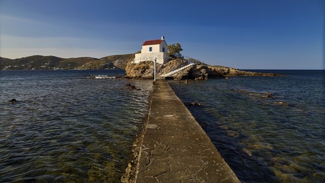 White chapel with red roof on a small island, connected to the mainland by a footbridge, chapel, church, Agios Isidoros, rocky islet, Bay of Gourna, Kokkali, Leros, Dodecanese, Greek Islands, Greece