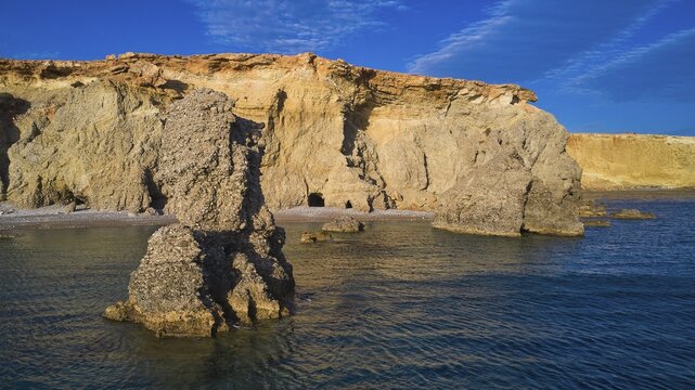 Sublime rock formation in front of a wild-looking cliff, drone shot, evening light, Araki Beach, southwest coast, Karpathos, Dodecanese, Greek Islands, Greece