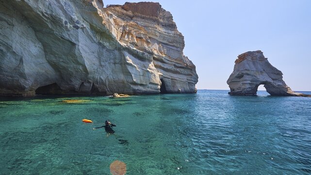 Divers in the water, rock gate in the water, pirate hideouts, caves, Kleftiko, tuff formations, sea turquoise, sea blue, sea green, caves, crystal clear water, lava rocks coloured, Milos Island, Cyclades, Greece