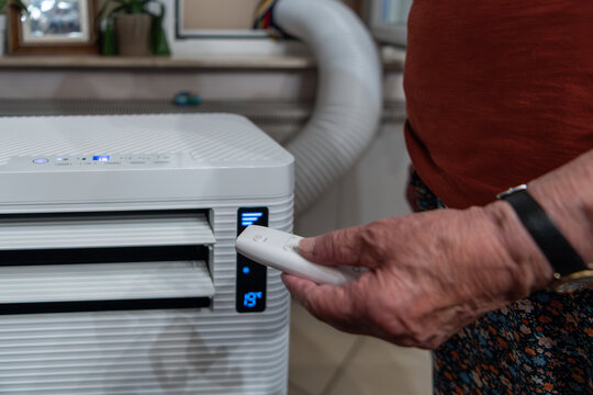Senior controlling portable air conditioner with remote control for indoor climate comfort