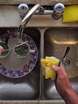 Manos lavando platos y tazas en la cocina