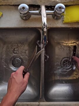 Manos lavando cubiertos en la cocina