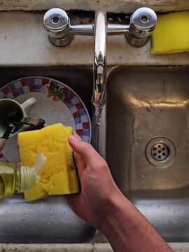 Manos lavando platos y tazas en la cocina