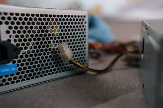 Computer power supply unit distributing electricity to components, showing its ventilation grid, ac in puta connected wire ready for installation or repair.