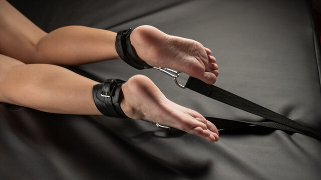 Women's legs in leather shackles. BDSM fetish.