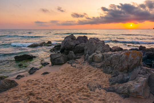 huge stones on a sandy beach at sunrise. wonderful summer vacation season at the black sea. calm waves washing the sand shore. nature background with cloudy sky. bulgaria travel photo
