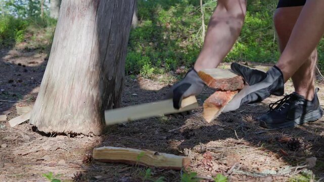 A close-up shot shows a man in protective work gloves gathering freshly split logs from the forest floor next to a chopping block.  Slow-motion at 24fps.