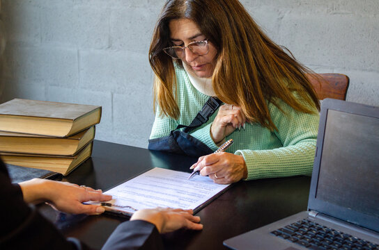 Injured woman signing compensation contract during meeting with lawyer
