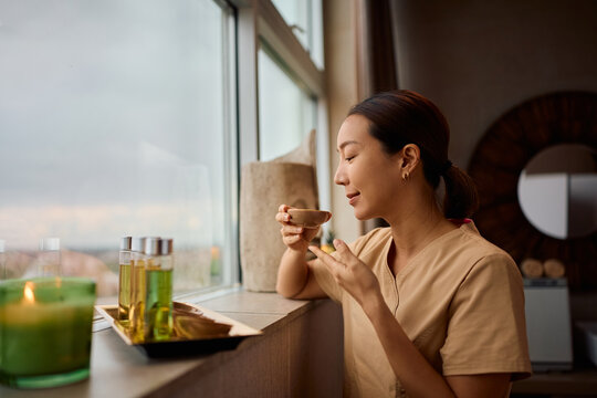 Female Korean wellness therapist preparing oils for spa treatment.