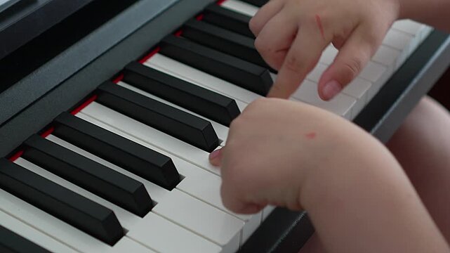 Child playing piano keys close-up