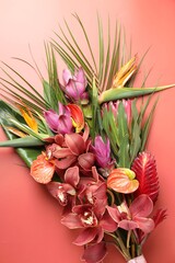 Fototapeta premium Bouquet of beautiful tropical flowers on red background, top view