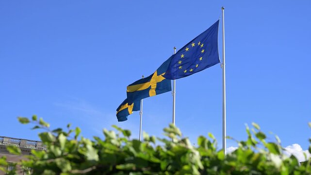Flags of Sweden and the European Union on flagpole. Swedish and EU flags against blue sky. Sweden officially joined the European Union on January 1, 1995.
