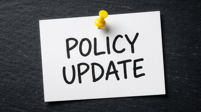 A white paper with policy update text held by a yellow pin on a dark background.