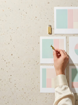 Vista superior de mano de mujer dise&ntilde;ando identidad de marca con paletas de colores, memoria USB dorada y fondo de terrazo