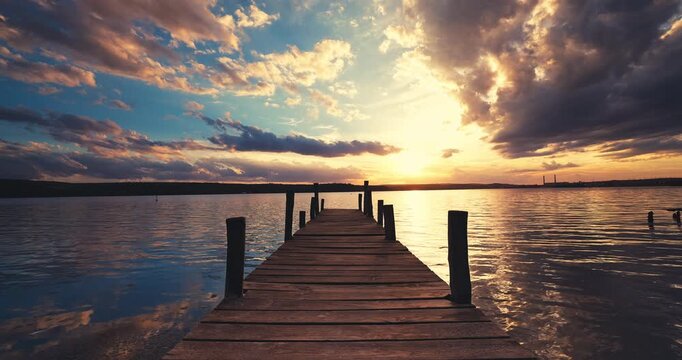 Scenic Sunset Over Wooden Fishing Jetty Pier on the lake With Gazebo Reflecting Golden Hour Colors