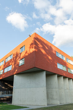 Hasselt, Belgium. Contemporary university campus architecture with red brick facade and concrete columns under blue sky