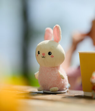 Cute plush bunny toy on outdoor picnic table.