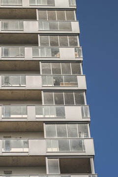 Tall modern apartment tower balconies against clear blue sky.