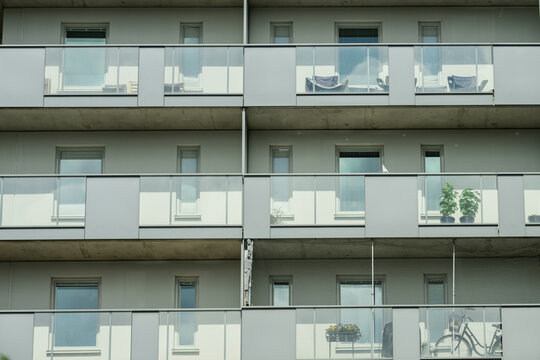 Modern apartment facade with balconies plants bicycle and glass railings.