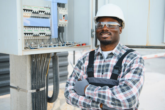 African american electrician working on electrical panel smiling