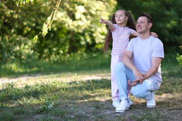 Fototapeta premium Smiling daughter showing something to her father outdoors. Space for text