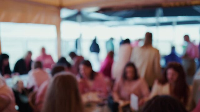 Blurred crowd of people gathered inside bright event venue with warm daylight and soft focus
