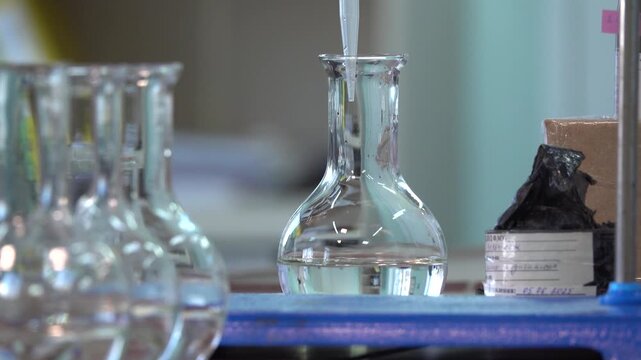Close-up footage of a laboratory experiment with test tubes and glassware, featuring bubbling and mixing liquids. Scientific research process in a modern lab environment, showcasing chemical reactions