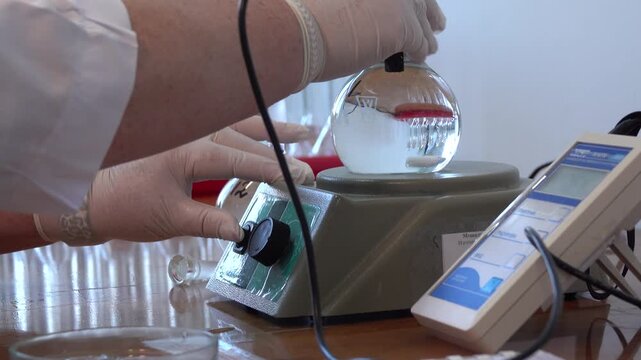 Close-up footage of a laboratory experiment with test tubes and glassware, featuring bubbling and mixing liquids. Scientific research process in a modern lab environment, showcasing chemical reactions