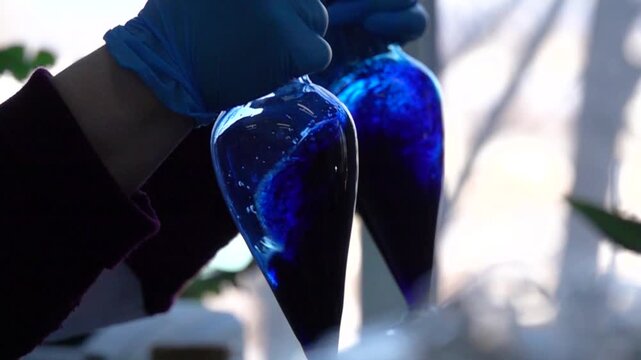 Close-up footage of a laboratory experiment with test tubes and glassware, featuring bubbling and mixing liquids. Scientific research process in a modern lab environment, showcasing chemical reactions