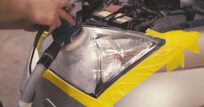Car polishing service car cleaner specialist polishing headlamp with polish machine in workshop garage