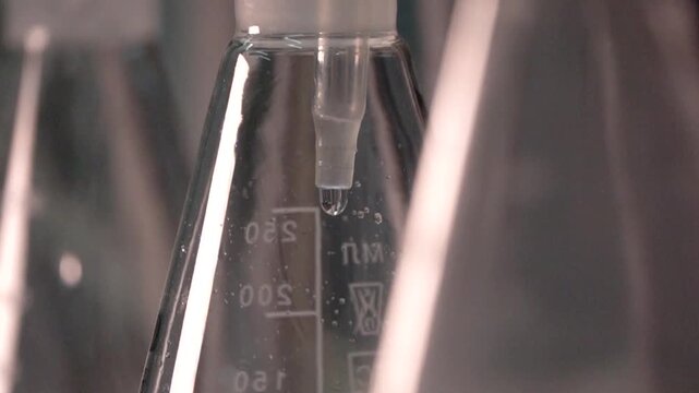 Close-up footage of a laboratory experiment with test tubes and glassware, featuring bubbling and mixing liquids. Scientific research process in a modern lab environment, showcasing chemical reactions