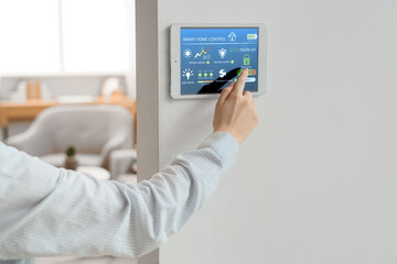 Person using smart home control panel on wall