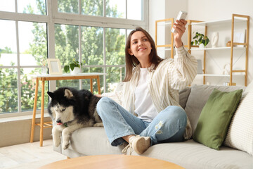 Young woman taking selfie with husky dog on sofa © Pixel-Shot